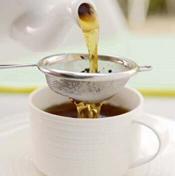 tea being poured over a tea strainer